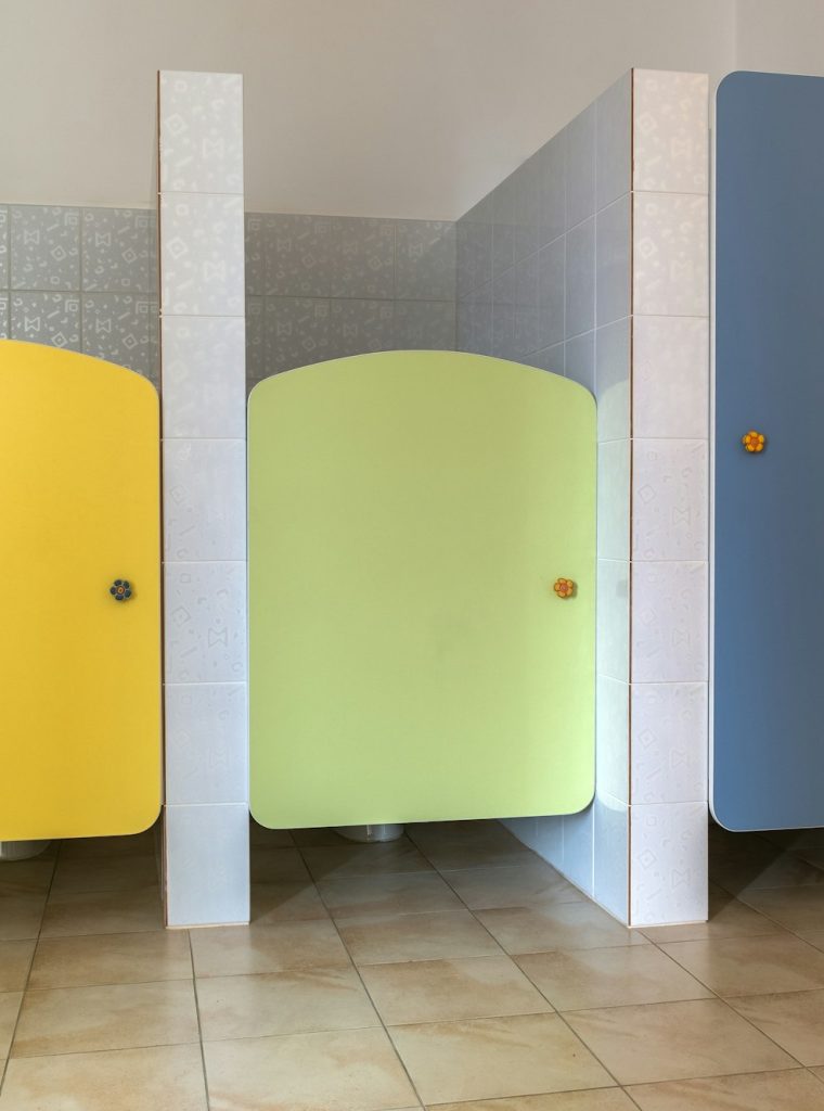Colorful toilet doors in elementary school bathroom interior